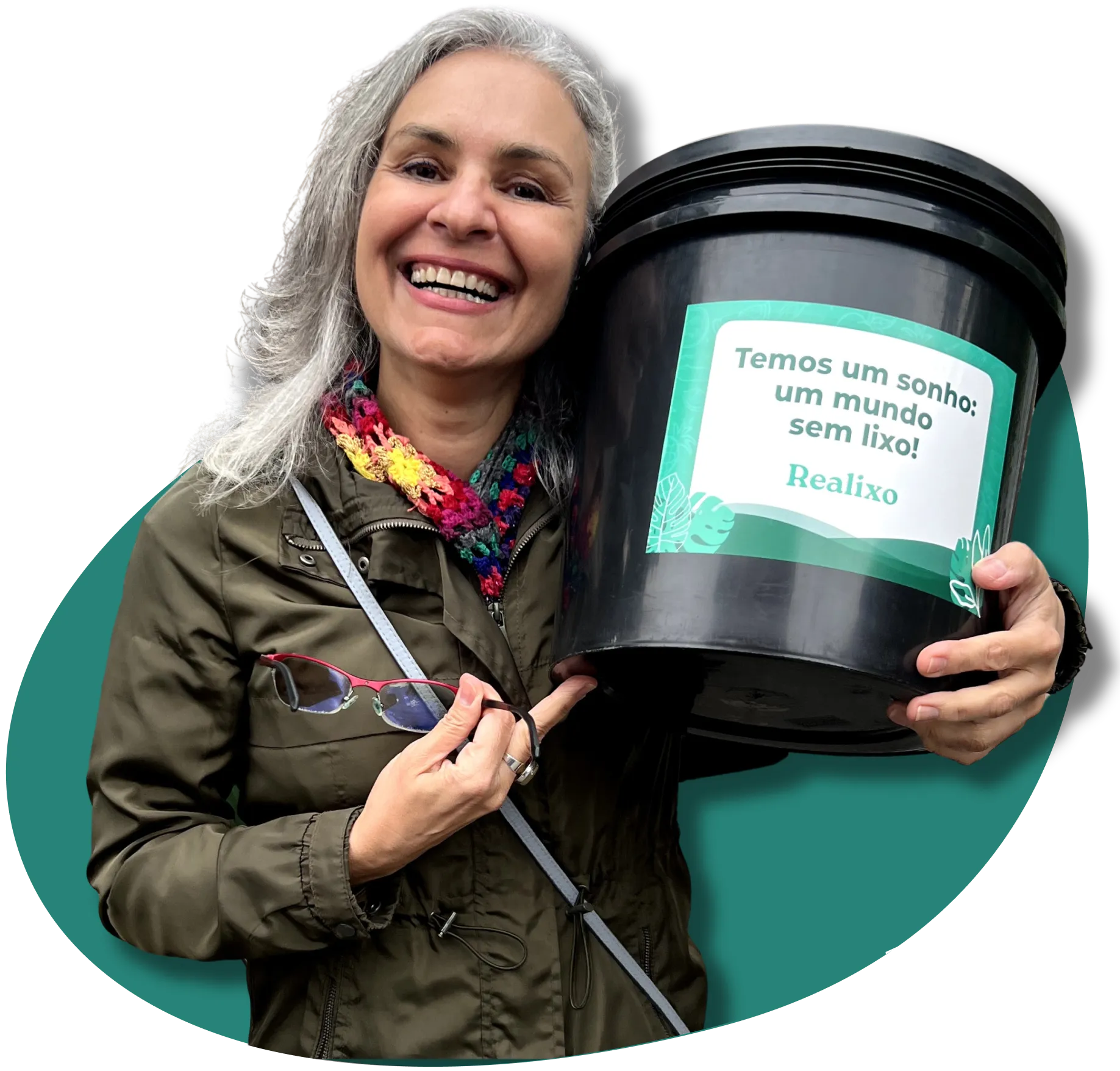Uma mulher com cabelos brancos em pé, segurando perto da cabeça um balde escrito Temos um sonho, um mundo sem lixo, atrás dela está um fundo verde